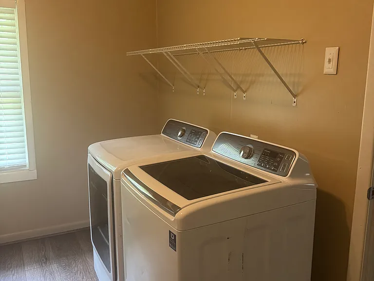 Laundry room with large washer and dryer with racks and cabinets