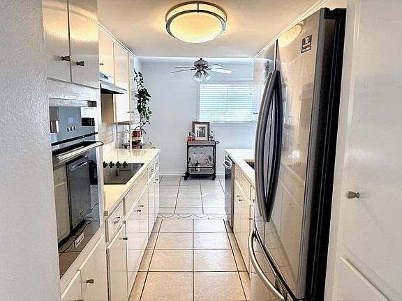 Kitchen with stainless French door refrigerator and stainless dishwasher. New 2025 white quartz counter, wall oven, black glass cooktop, stainless sink and faucet.