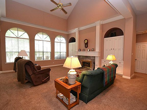 Spacious family room featuring high cathedral ceilings, ceiling fan, fireplace with gas logs, built-