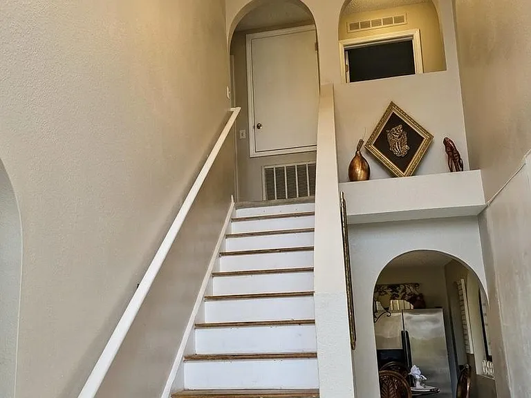 Two-story entry hall with staircase, high ceiling, and statement chandelier, opening to an adjacent dining area.