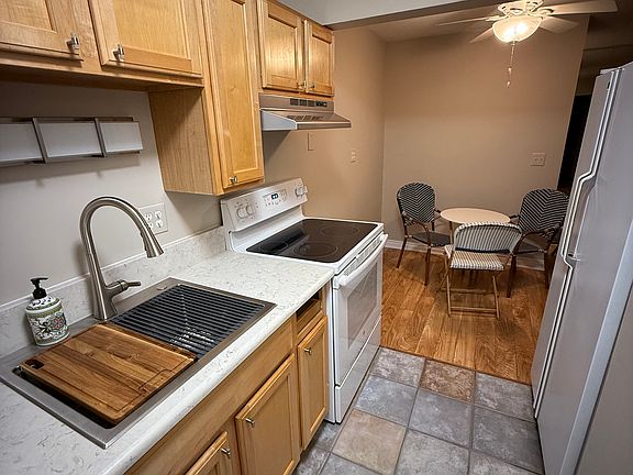 Kitchen looking into dining nook. Electrics stovetop oven, French door fridge and microwave.