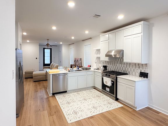 Bright kitchen with brand new stove, exhaust fan, dishwasher, and sink.
