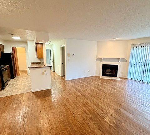 View of the living room, kitchen, and hallway to the entry and primary bedroom from the second bedroom