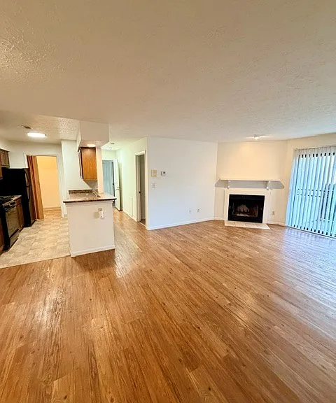 View of the living room, kitchen, and hallway to the entry and primary bedroom from the second bedroom