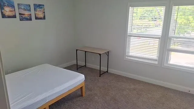 Carpeted bedroom with a large window for natural light, plus space for a desk or additional storage. - Marble St