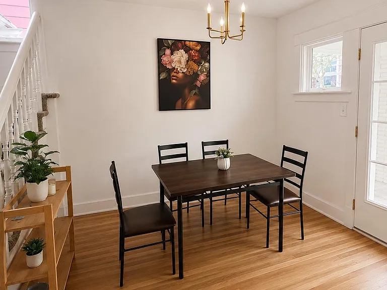 Dedicated dining area with a 4-seat table, hardwood-style floors, and convenient access to the entry and stairs.