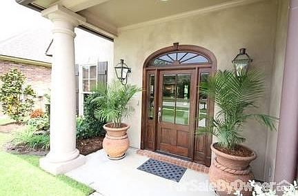 The open porch, beautiful door & gas lanterns creates an inviting entrance