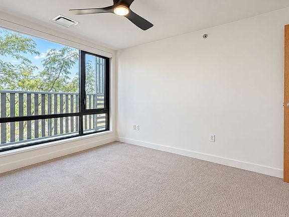Brighten your day in this airy Farmers Park Apartments home, featuring large windows, soft carpeting, a ceiling fan, and a private balcony. Explore available apartments today!