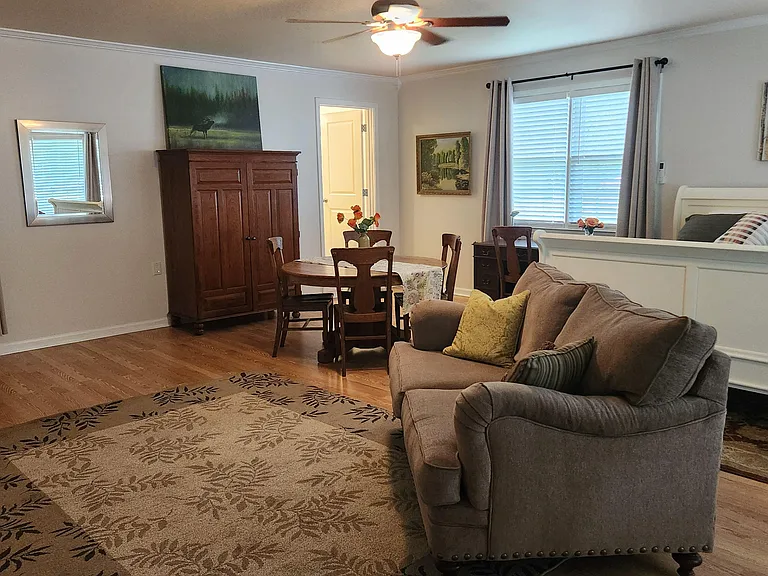 Spacious bedroom with a sitting area, hardwood floors, a desk nook, and an armoire for extra storage.