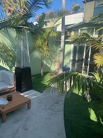 Patio entry area/yard, outdoor furniture space, plants and palm trees.