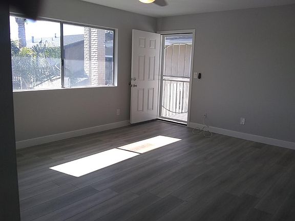 Living room, with new flooring paint, ceiling fan, front door and security screen.