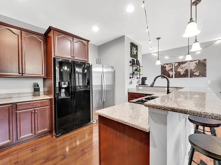 Spacious kitchen with granite counters, ample cabinetry, breakfast bar seating, and full-size stainless appliances.