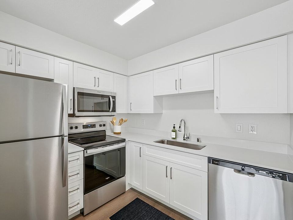 Renovated Package II kitchen with stainless steel appliances, updated white cabinetry, quartz countertops, and hard surface flooring