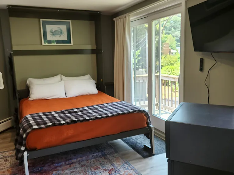 Bedroom 3 with queen bed on second floor, separate entrance, mini-fridge, mircowave, smart TV, fold away table and chairs, shower stall, bathroom sink, toilet, and views of backyard.