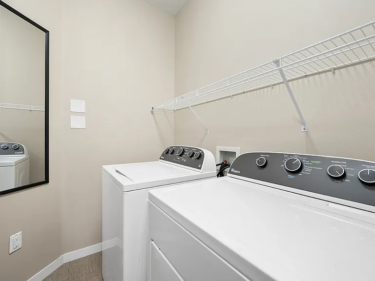 Modern laundry room featuring energy-efficient washer and dryer with sleek shelving. Modern laundry room featuring energy-efficient washer and dryer with sleek shelving.