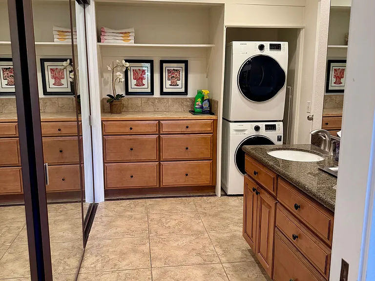 Primary bath with double sinks, large closet on left and washer/dryer.