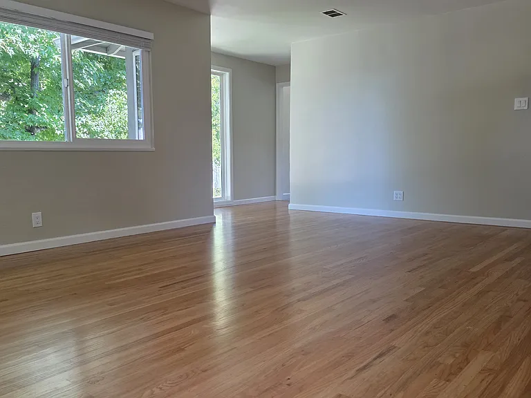 Large living room with hardwood floors and dual pane windows. View from farthest corner from front door.