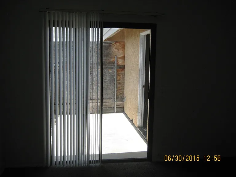 Large sliding Patio Door out to the very large patio. Beyond patio is private parking with 3 spots. Sorry picture looks dark but room is white and bright. Come see it! !