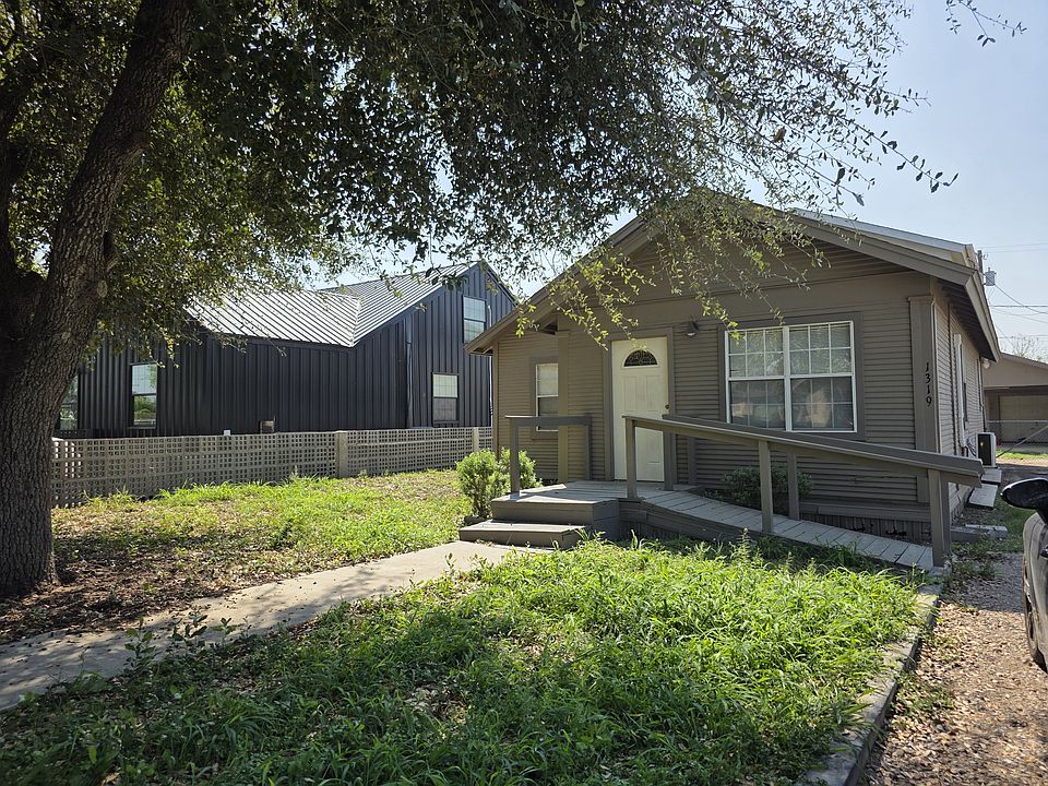 Front of the house with a ramp. Driveway leads to carport and two-car garage with storage room.