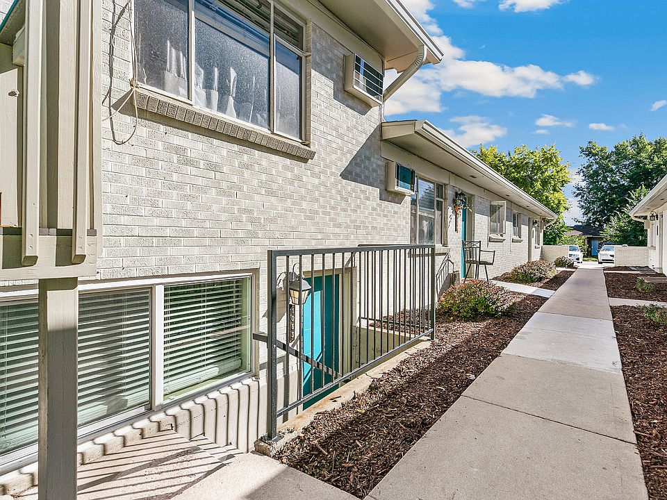 Charming apartment exterior with modern brick facade, inviting walkway, and well-maintained landscaping under a bright blue sky.