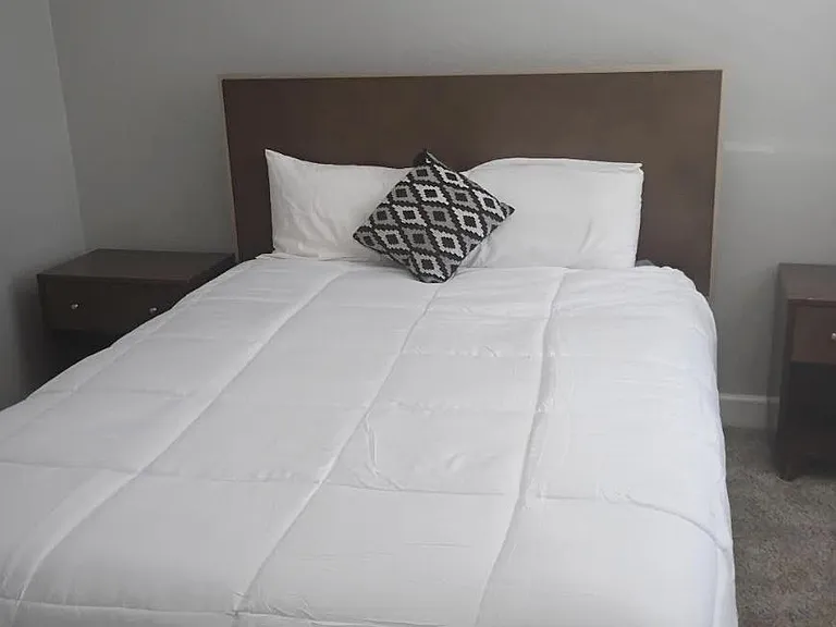 Neat bedroom with a full bed, simple headboard, and matching nightstands on soft carpet for easy everyday living.