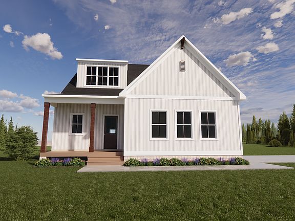 White house in Poplar Village with black roof, surrounded by grass and trees, under a blue sky with