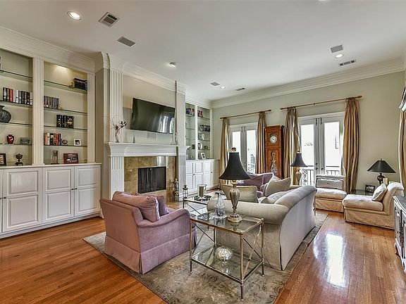 The main living room is located on the second floor.  Custom cabinetry with shelves frame the welcoming fireplace.  Gorgeous hardwoods throughout the second floor.  Natural light fills the room from the french doors, which all open to Juliet balconies.
