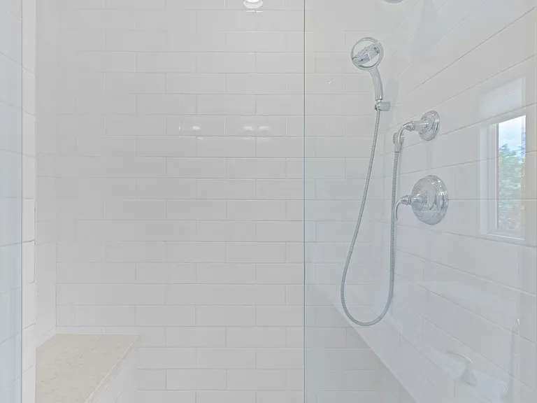 The walk-in shower features classic subway tile detailing and a built-in bench for added comfort and functionality.