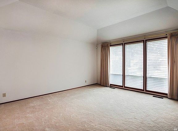 Large living room with vaulted ceilings and custom blinds.