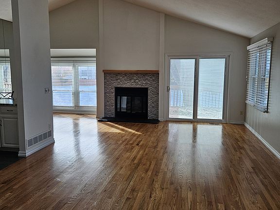 Vaulted ceiling in main living area with skylights. Natural hardwood floors and sliding patio door.