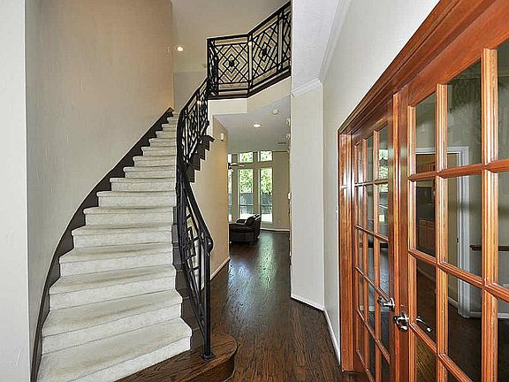 Entry has sweeping staircase with wrought iron baluster, french doors lead to formal dining room