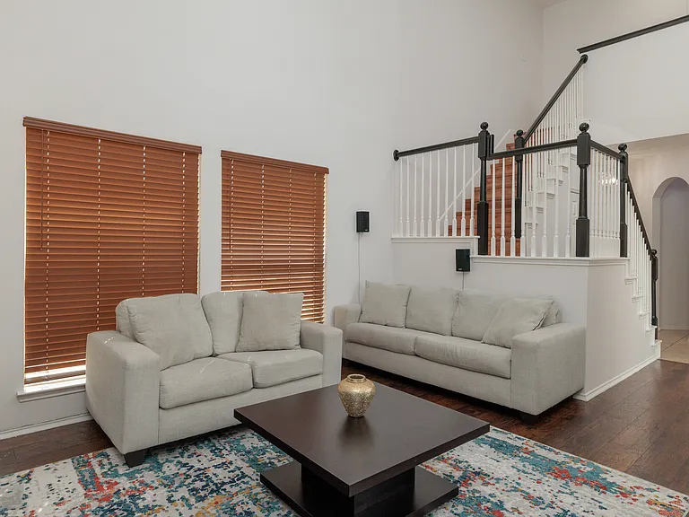 Spacious living room with couch, love seat and TV.