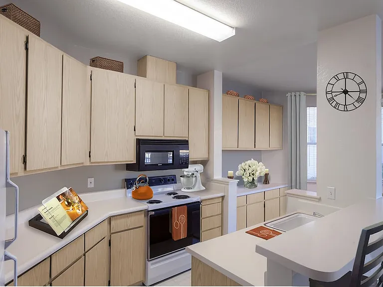 Classic Package I kitchen with light oak cabinetry, white laminate countertops, black appliances, and hard surface flooring