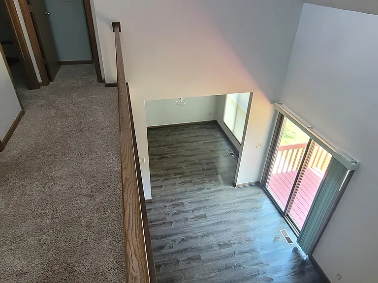 View from the upper level showcasing the lower level living room and dining room. First door on the left is the bathroom followed by 2 bedrooms.