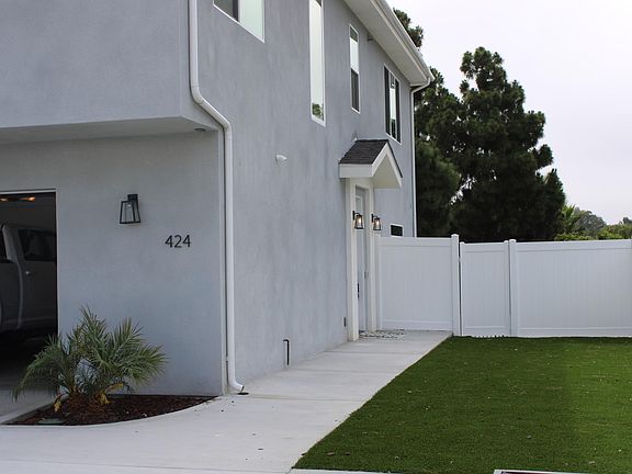 view of home from inside the gated community. Side yard leads to front door of home. two car garage