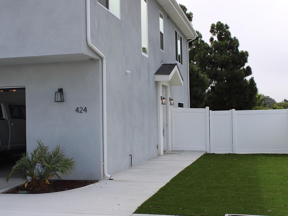 view of home from inside the gated community. Side yard leads to front door of home. two car garage