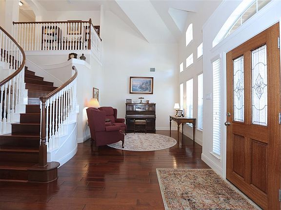 As you enter the home, the formal living room is to your right, with soaring ceilings and rich, warm wood floors.