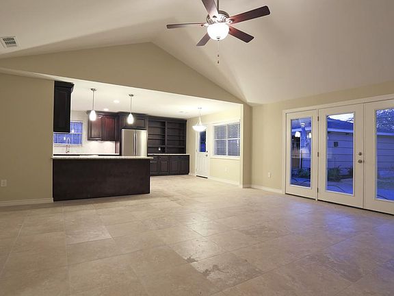 Gorgeous cathedral ceilings in the living room provides plenty of room for entertaining. The living room features french doors, oversized stone-finish tile floors, recessed lighting, and pre-wired for tv mounting.