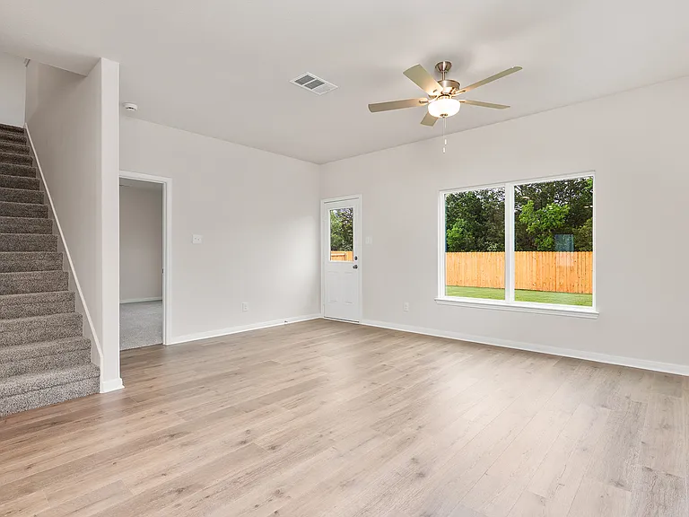 The living room is spacious and has a large window that lets in natural light.