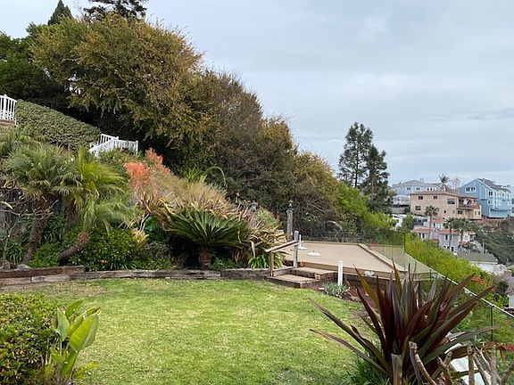 View of the large back yard, entertainment deck and glass fence.