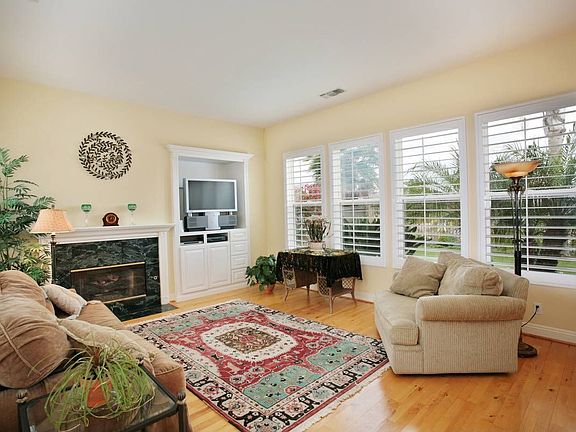 Family room with marble surround fireplace, and plantation shutters.