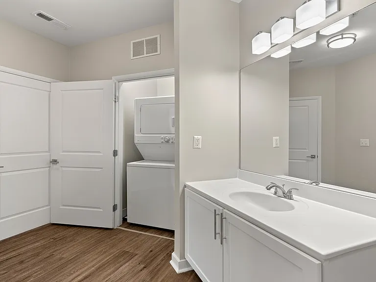 Modern bathroom featuring a large vanity, plus laundry neatly tucked away for added convenience