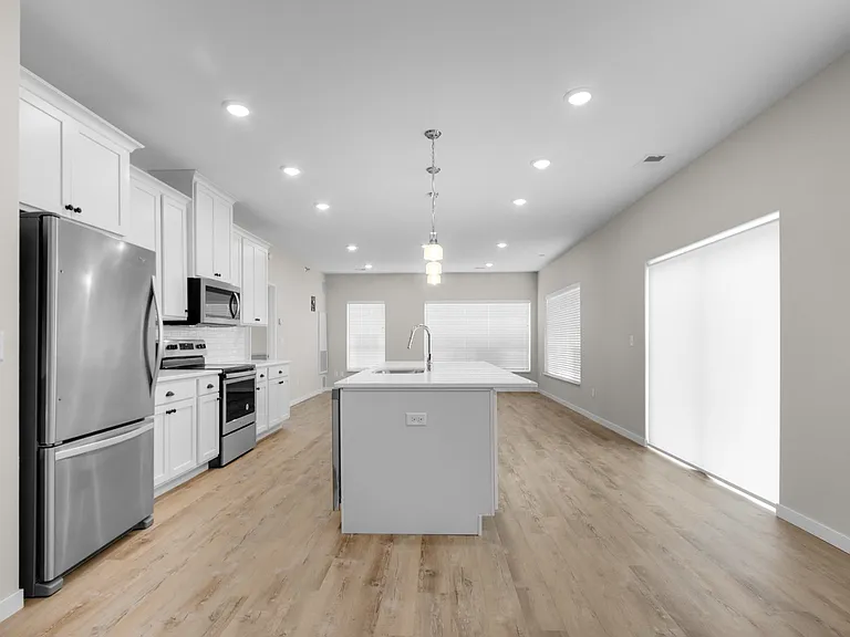 Spacious modern kitchen with sleek stainless steel appliances, elegant cabinetry, and a large central island in a bright open-concept layout. Spacious modern kitchen with sleek stainless steel appliances, elegant cabinetry, and a large central island in a