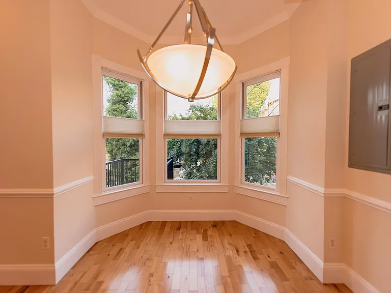 Dining room with decorative chair rail, crown molding, and double-bay windows that overlook rear deck and semi-private garden