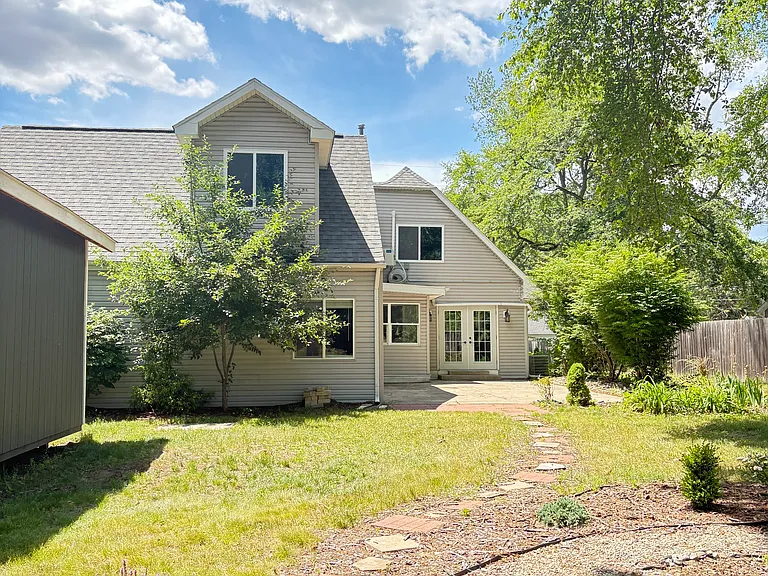 The charming backyard offers a dedicated fire ring area with landscaping, a spacious patio beside the home, and additional outdoor space ideal for families.