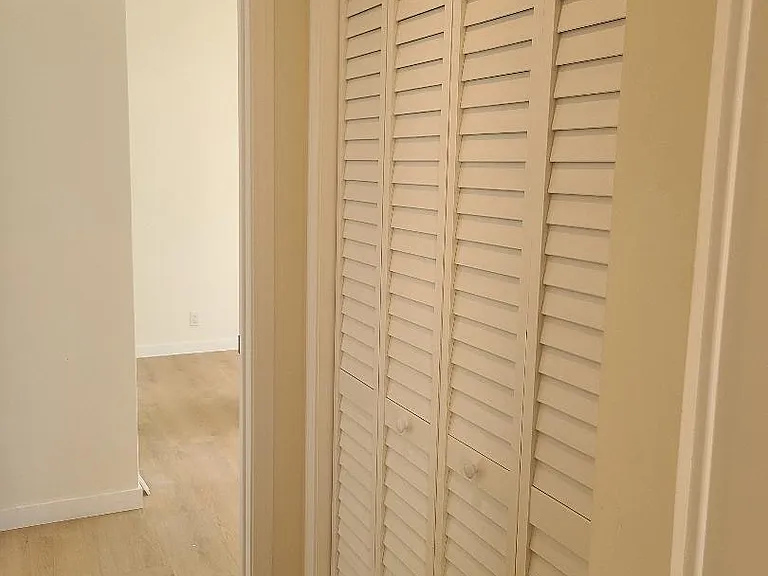 Louvered doors in hallway covering washer and dryer
