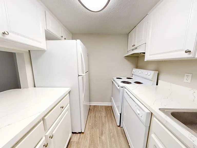 Modern kitchen with sleek white cabinetry, spacious countertops, and stainless steel appliances on elegant wood flooring. Modern kitchen with sleek white cabinetry, spacious countertops, and stainless steel appliances on elegant wood flooring.
