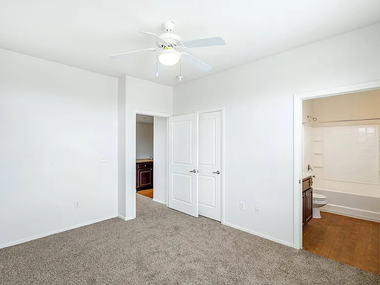 Enhance your space with the simplicity and freshness of a bedroom adorned with pristine white walls and a sleek ceiling fan, providing both style and comfort