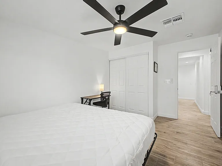 Bedroom includes a ceiling fan with light, sliding-door closet, and space for a bed plus a dedicated desk area.
