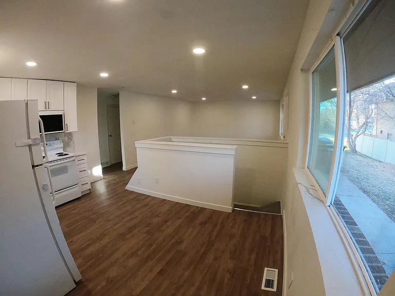 View from back door. Here you can see the quartz windowsill, staircase leading to the basement, kitchen, and an open view of the living room.